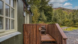 A wooden staircase leading to a wooden deck with a bench, surrounded by a green building with windows and a sign reading "Lodge." - Juniper Lodge, Shepherd's Hut  for 2 in the Lake District with exclusive hot tub (Coniston)