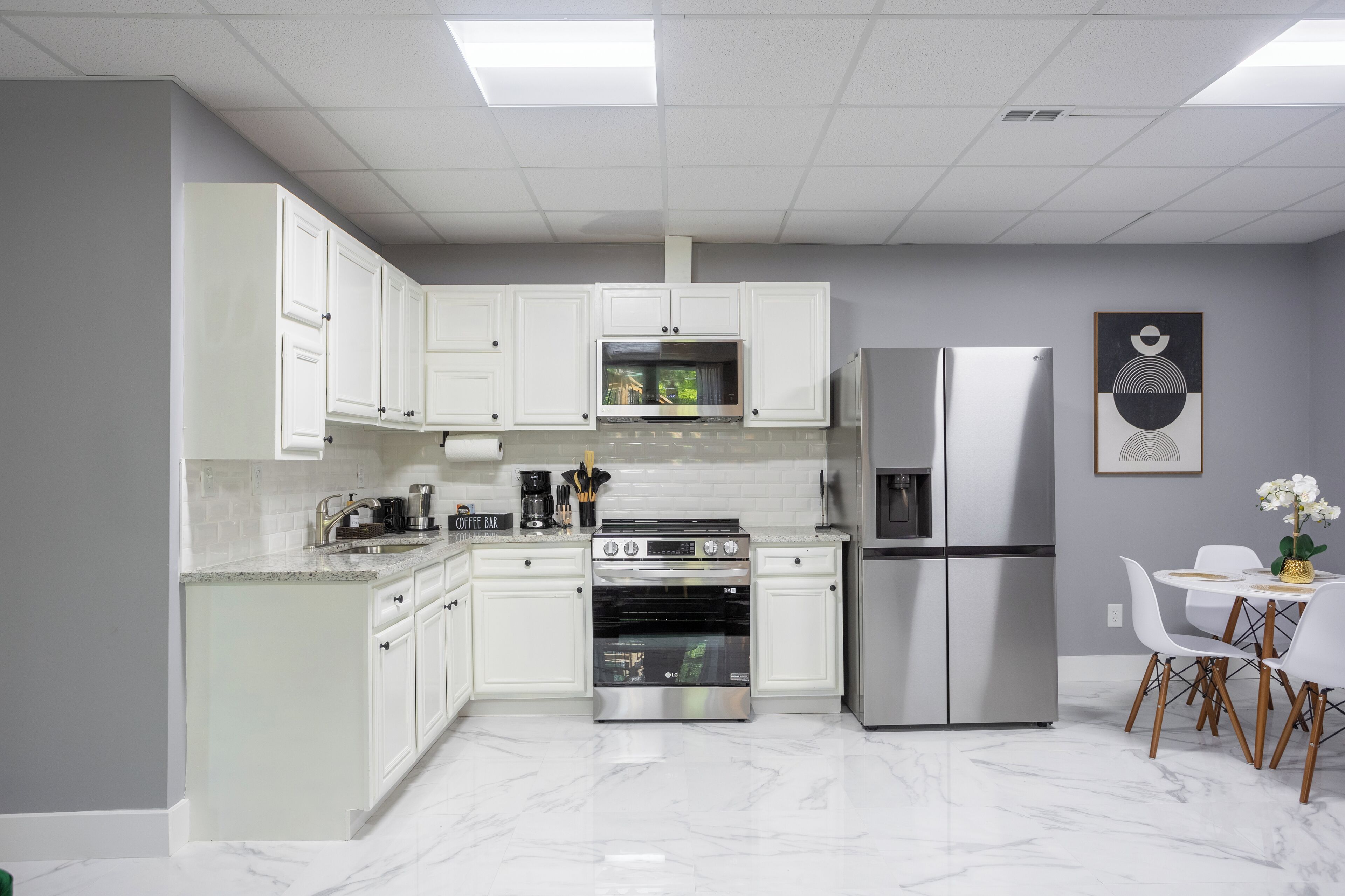 Uma cozinha moderna com armários brancos, eletrodomésticos de aço inoxidável e bancada de mármore.