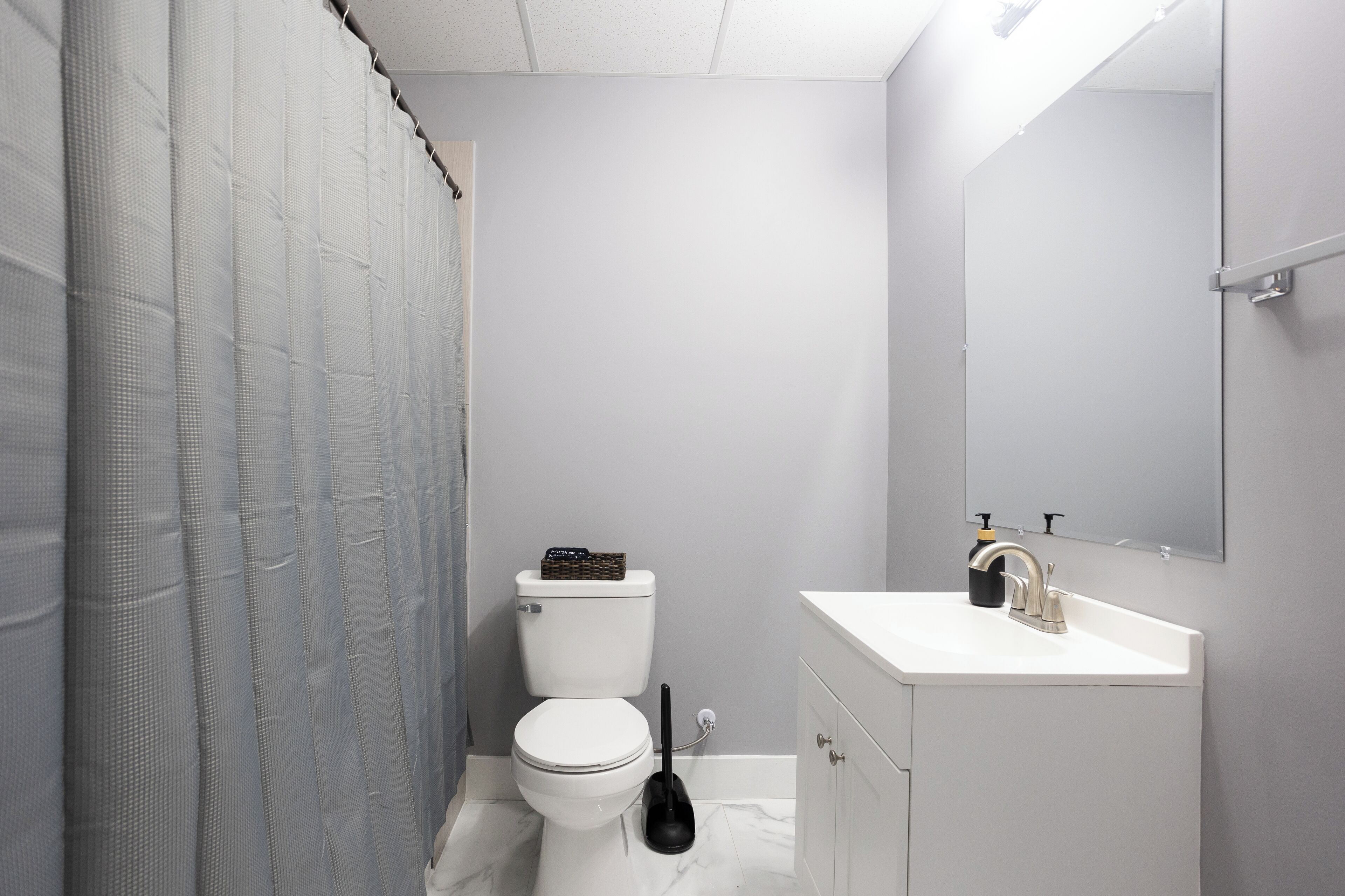 A bathroom with a toilet, sink, and mirror.