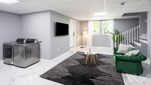 A modern living room with a grey wall, a flat-screen TV, a green sofa, and a black and white rug. - Charming 2-bedroom apartment in delightful Decatur with AC (Decatur)