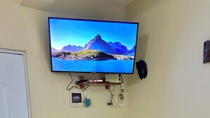 Ett rum med en tv monterad på väggen som visar en vacker utsikt, ett litet bord med stolar och en dörr.