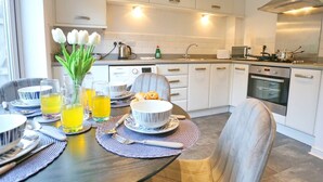 Una cocina moderna con armarios blancos, electrodomésticos de acero inoxidable y un comedor listo para una comida.