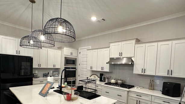 A modern kitchen with white cabinets, a black stove, and pendant lights. - Luxury and Executive 4-bedroom house, Close to Blue Oval City (Arlington)