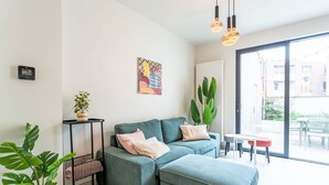 Een moderne woonkamer met een hoekbank, een bijzettafeltje en potplanten.
