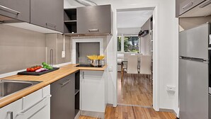A modern kitchen with a wooden countertop, stainless steel appliances, and a view into the dining area.