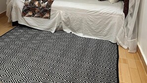 A single bed with a white canopy and patterned throw blanket, a black and white geometric rug, and a plain wall. - Royal Guest House Kipkorgot (Eldoret)