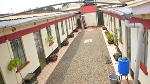 A courtyard with a gravel path, potted plants, and a blue water tank. - Royal Guest House Kipkorgot (Eldoret)