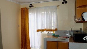 A small kitchen with a window, a sink, and a microwave. - Royal Guest House Kipkorgot (Eldoret)