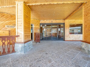 A wooden building entrance with a sign for the ski room, a glass door, and a stone-tiled floor. - Le Sérac by Interhome (Val Thorens)