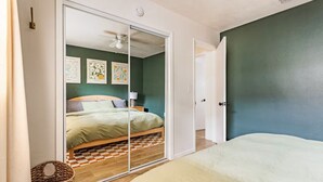 Un dormitorio con cama, armario y ventilador de techo.
