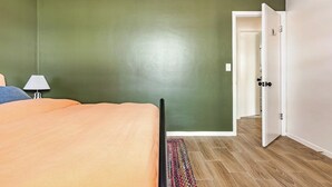 A bedroom with a bed, a nightstand, a lamp, a door, and a patterned rug. - Updated 2 BR / 5 min to Advent Health / Walk to Museums, Parks & Dining. (Orlando)