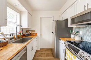 Une cuisine moderne équipée d’un lave-vaisselle Bosch, d’un réfrigérateur en acier inoxydable et d’un four à micro-ondes.