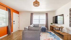 Una sala de estar moderna con un sofá, una mesa de centro, un televisor y un tapete estampado.
