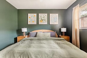 A bedroom with a bed, two bedside tables, and three framed pictures on the wall.