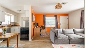 Un espacio habitable moderno con cocina, comedor y zona de estar con sofá y mesa de centro.