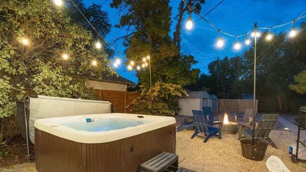 A hot tub with steps, surrounded by outdoor seating and a fire pit, under string lights. - Pet-friendly Getaway near Cheyenne Cañon&Ivy wild (Colorado Springs)