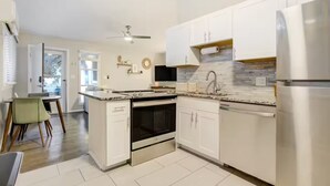 A modern kitchen with white cabinets, a stainless steel refrigerator, and a tiled backsplash. - Pet-friendly Getaway near Cheyenne Cañon&Ivy wild (Colorado Springs)