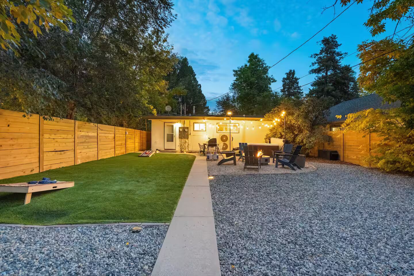 A backyard with a patio area, a hot tub, and a wooden fence.