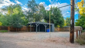 A covered outdoor area with a gravel ground, a metal roof structure, and a wooden fence in the background. - Pet-friendly Getaway near Cheyenne Cañon&Ivy wild (Colorado Springs)