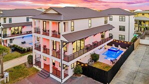 A multi-story residential building with a rooftop pool, balconies, and a well-maintained lawn. - Arcadia Sands: Private Beach, Ocean Views, Pool & Hot tub, Game Room, Bunk Rooms (Miramar Beach)