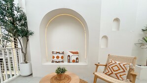 Un interior moderno con una mesa redonda de madera, una silla tejida y un banco con cojines.