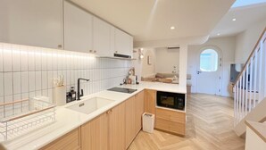Una cocina moderna con armarios blancos, un grifo negro y suelo de madera.