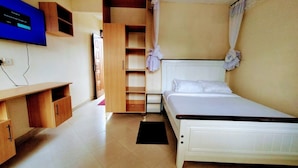 A bedroom with a bed, a wardrobe, a TV, and a small window. - Kusi hotel Kakamega (Kakamega)