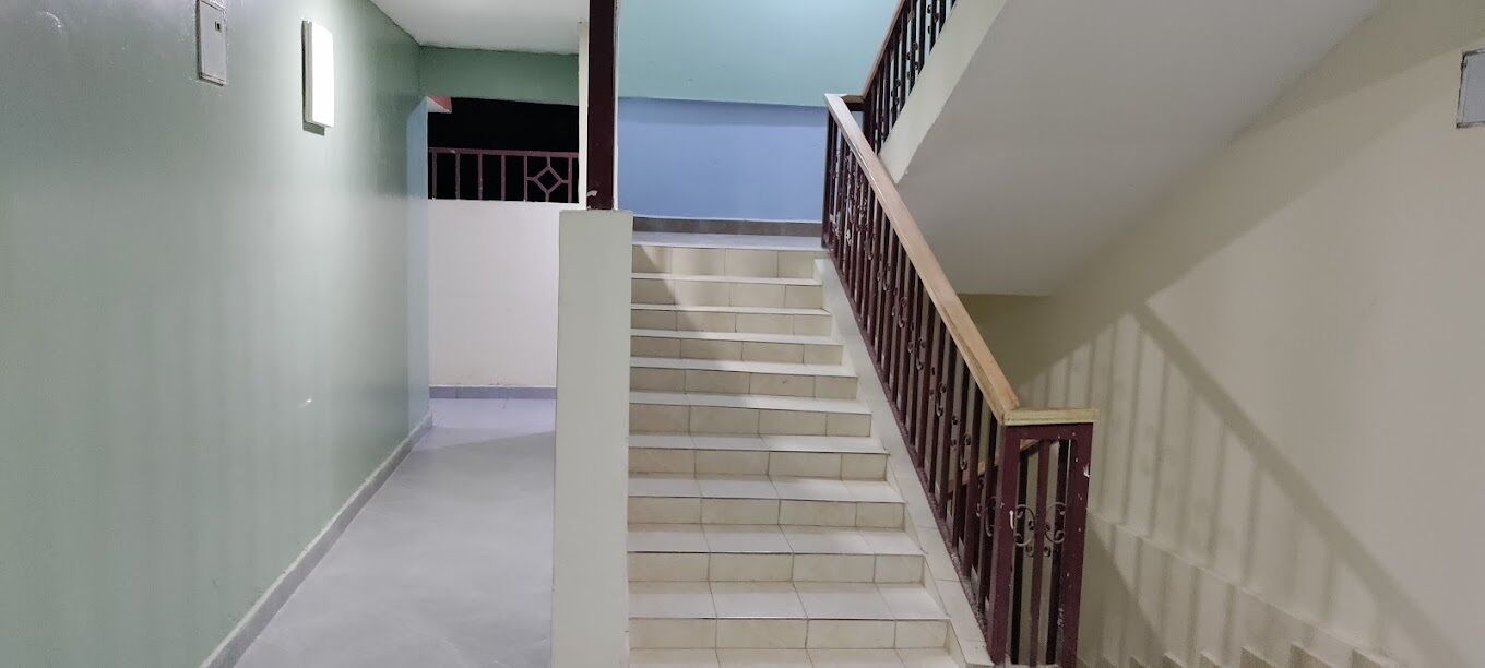 Una escalera con barandilla y una reja metálica en la parte superior.