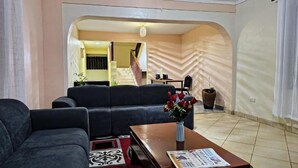 A living room with a sofa set, a coffee table with a newspaper, and a vase with flowers. - Kusi hotel Kakamega (Kakamega)