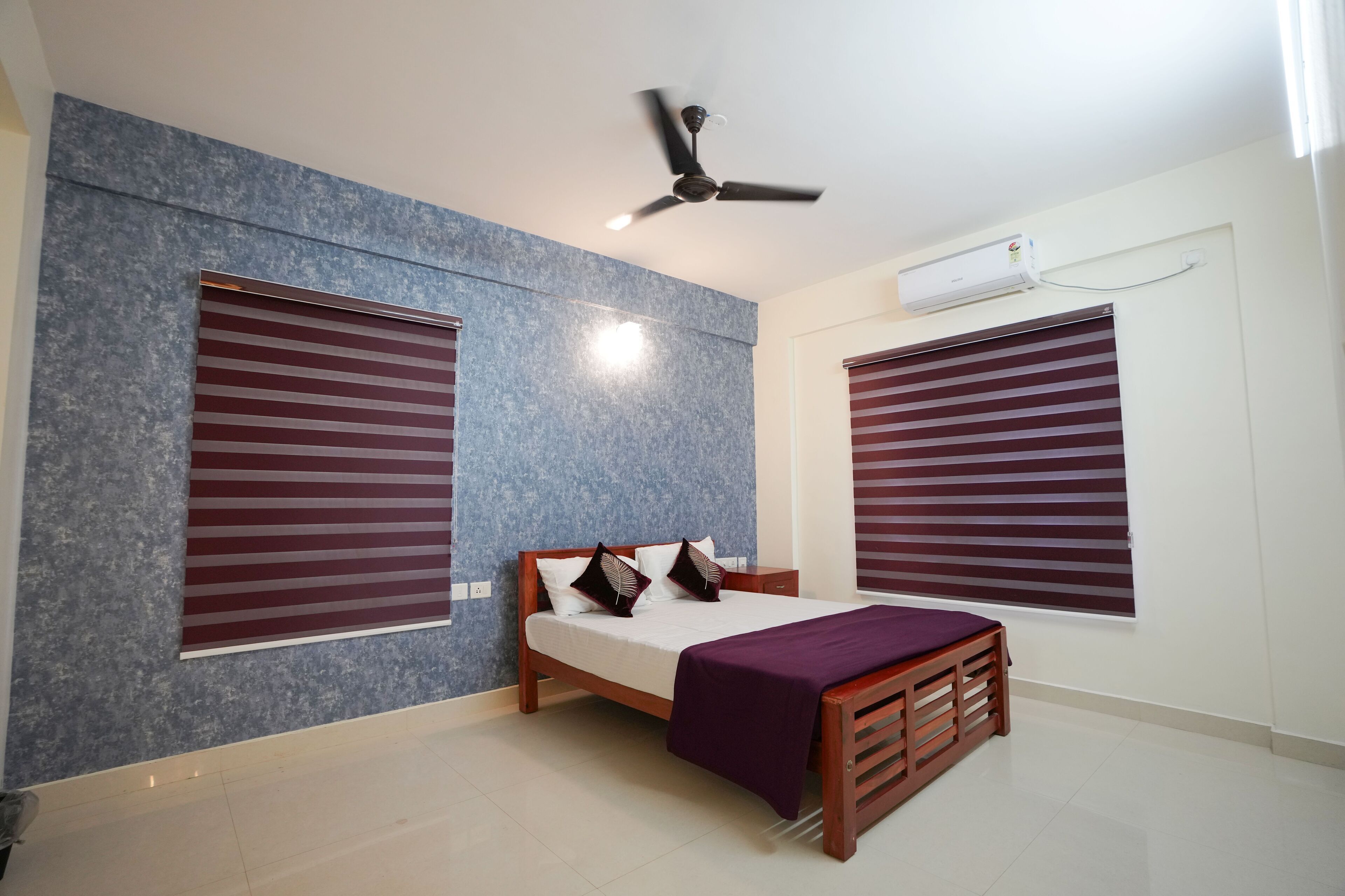 A bedroom with a bed, a ceiling fan, and an air conditioning unit.
