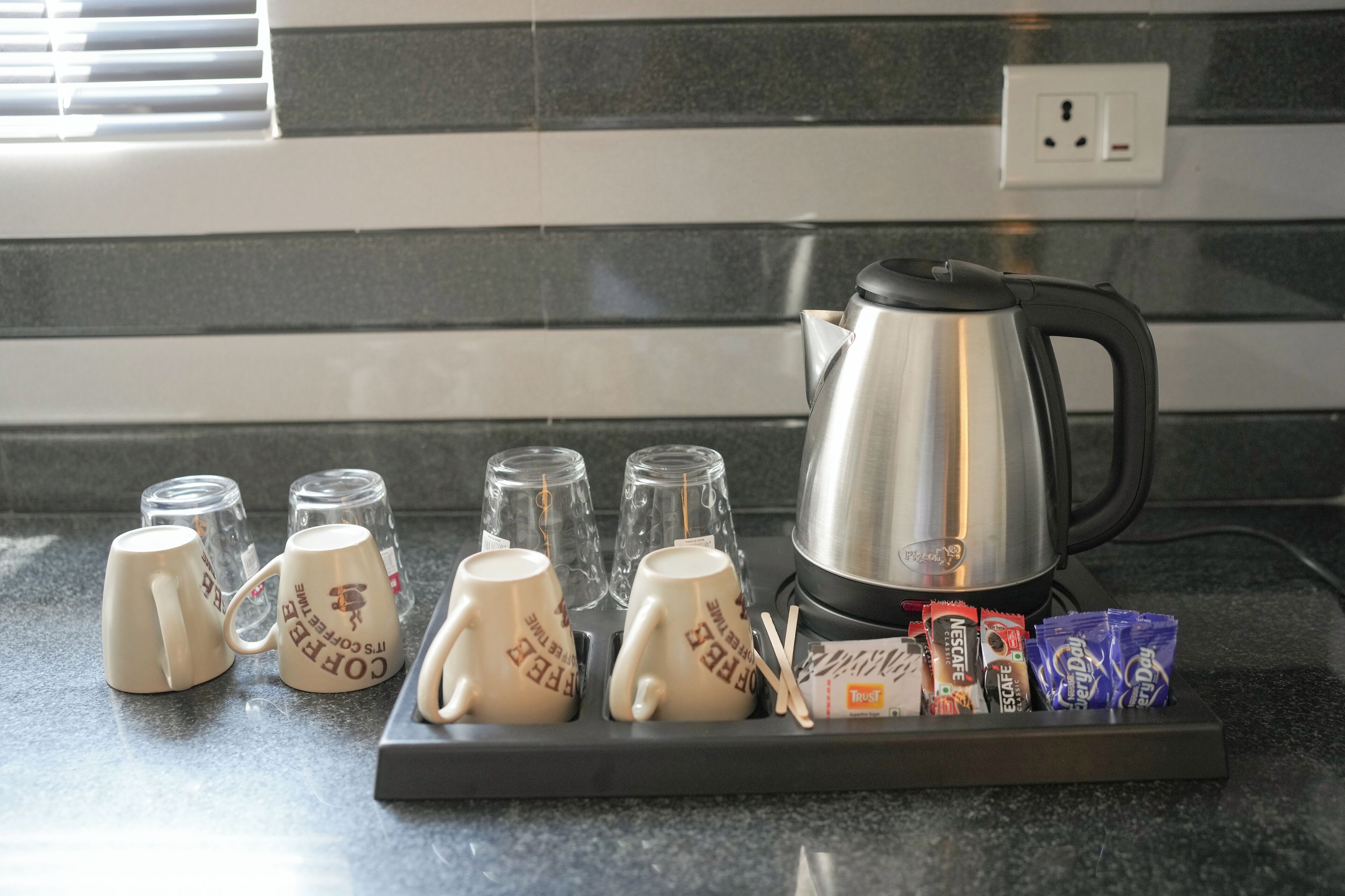 Una encimera de cocina con cafetera, tazas y aperitivos.