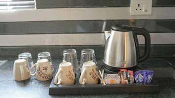 Una encimera de cocina con cafetera, tazas y aperitivos.