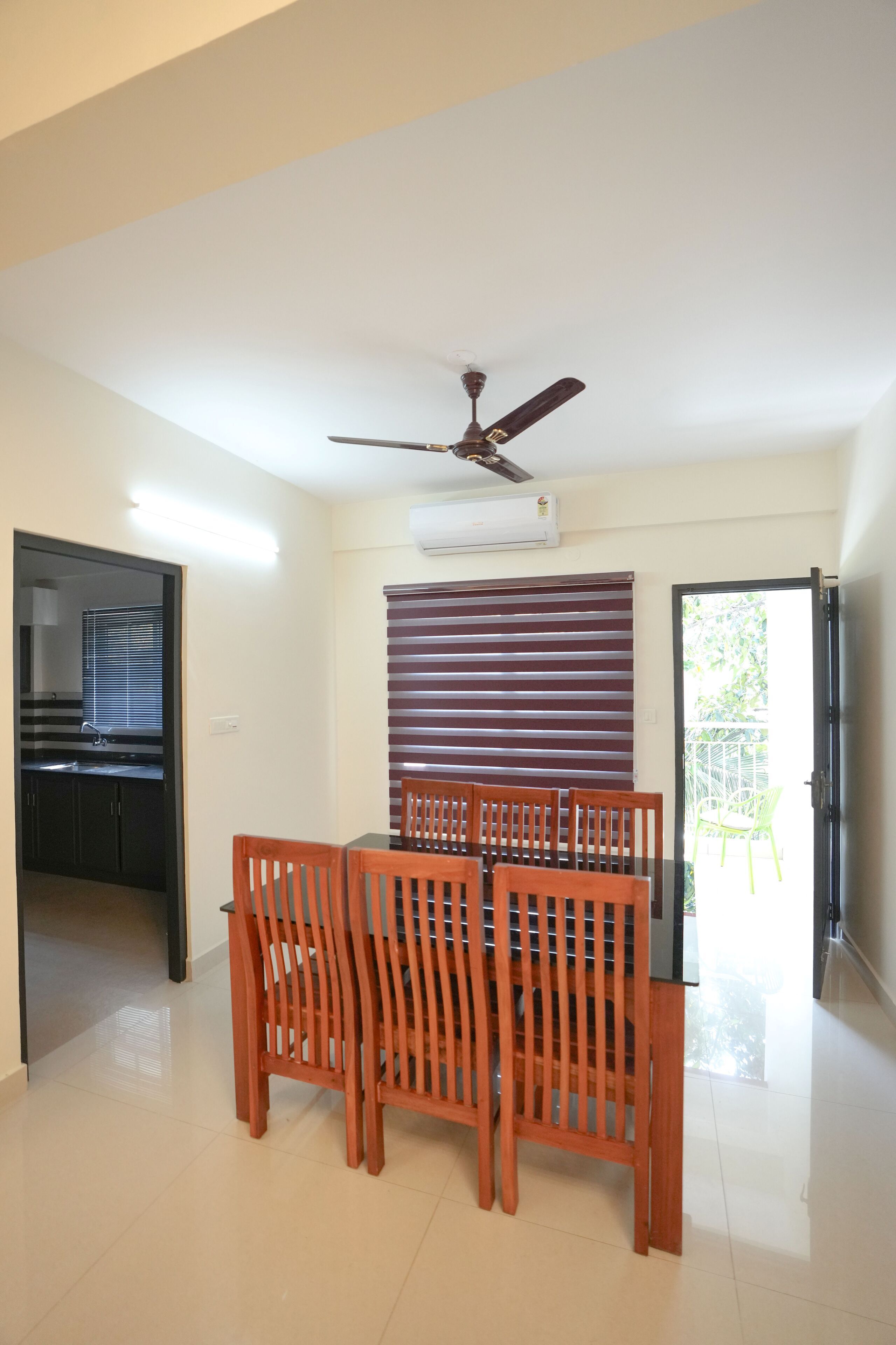 A dining area with a table and chairs, a ceiling fan, an air conditioning unit, and a view of the outside.