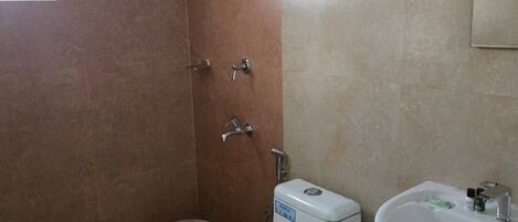 Une salle de bain comprenant des toilettes, un bidet, un lavabo et une douche.
