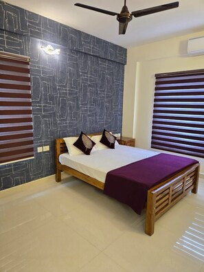 A bedroom with a bed, a ceiling fan, and a window with blinds. - Centur Apartments (Changanassery)