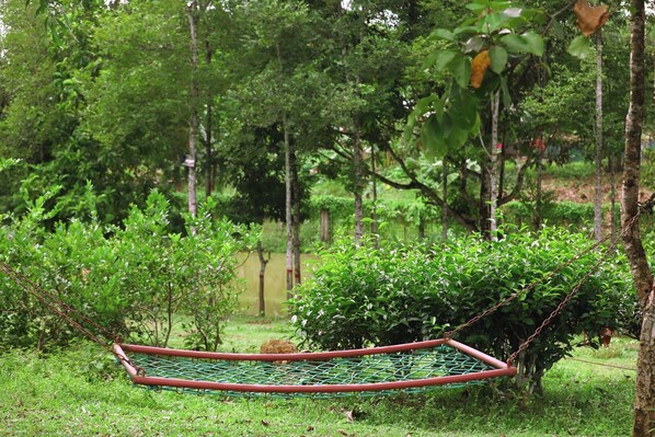 A hammock in a lush green outdoor setting. - Swiss Valley Resort (Kamalganj)