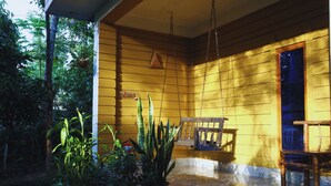 A room with yellow walls, a wooden bench, and potted plants. - Swiss Valley Resort (Kamalganj)