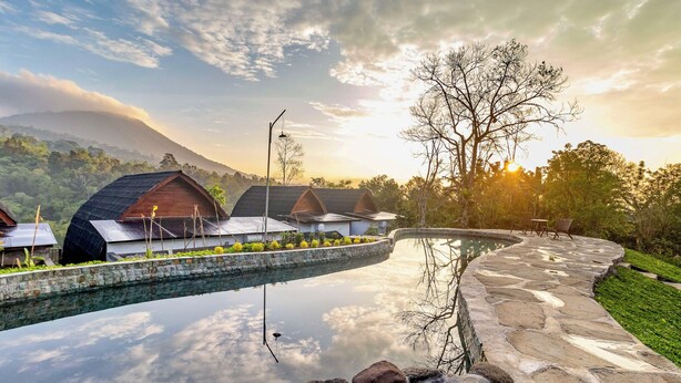 Een resort met een zwembad, een pad van stenen en meerdere bungalows.