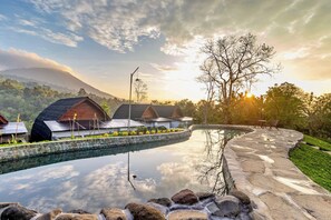 A resort with a swimming pool, stone pathway, and several bungalow-style cabins. - Shankara Forest Haven Villa by AGATA (Penebel)