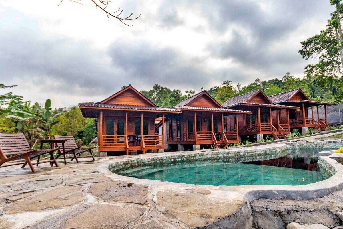 A wooden bungalow-style resort with a swimming pool.