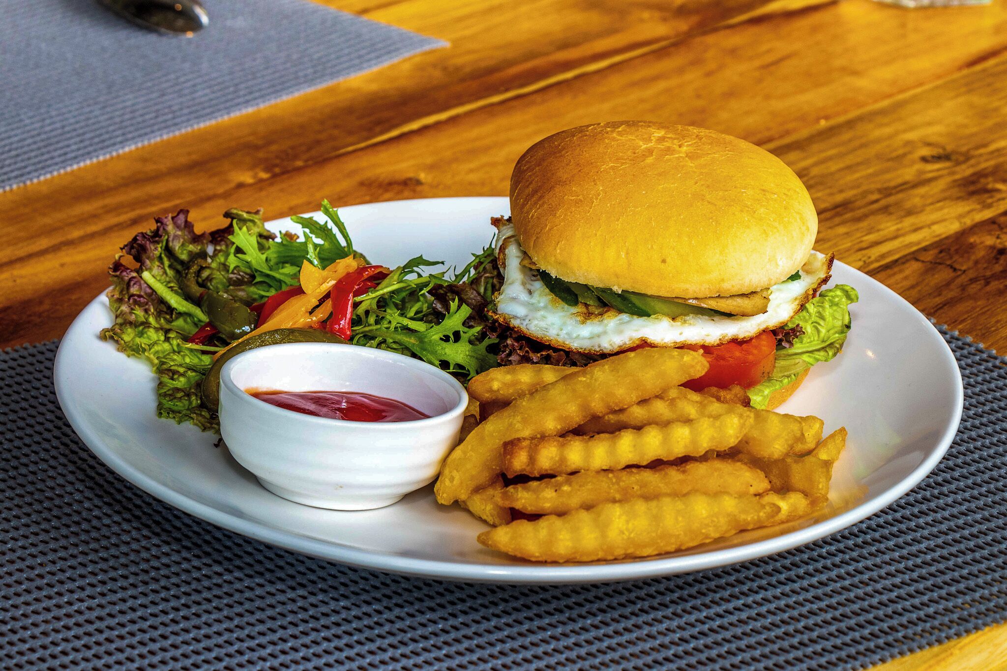 A plate with a burger, fries, and a side salad with ketchup.