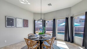 Un coin repas avec une table ronde, des chaises en osier et un luminaire suspendu.