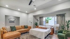 Une chambre à coucher moderne avec un lit, deux canapés, une grande fenêtre avec des rideaux et un ventilateur de plafond.