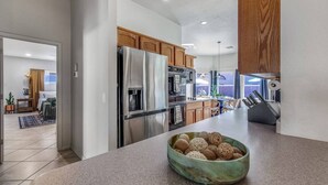 Une cuisine moderne dotée d’appareils électroménagers en acier inoxydable, de meubles en bois et d’un grand îlot central agrémenté d’un récipient contenant des objets décoratifs.