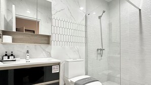 Une salle de bain moderne avec un meuble-lavabo en marbre, des toilettes et une douche à parois de verre.