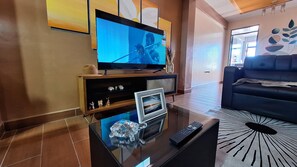 A modern living room with a flat-screen TV, a coffee table with a remote, and a sofa. - Enjoyable 2-bedroom, 2-bathroom apartment with heating and Wi-Fi in Uyuni (Uyuni)