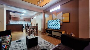 Un saló modern amb televisió, zona de menjador i cuina al fons.