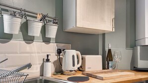 A kitchen with a Bosch toaster, a sink, a cutting board, and a wine bottle. - 2 bedroom accommodation in Tideswell (Tideswell)