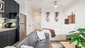 A compact living space with a kitchenette, a sofa, a bed, and a dining area.