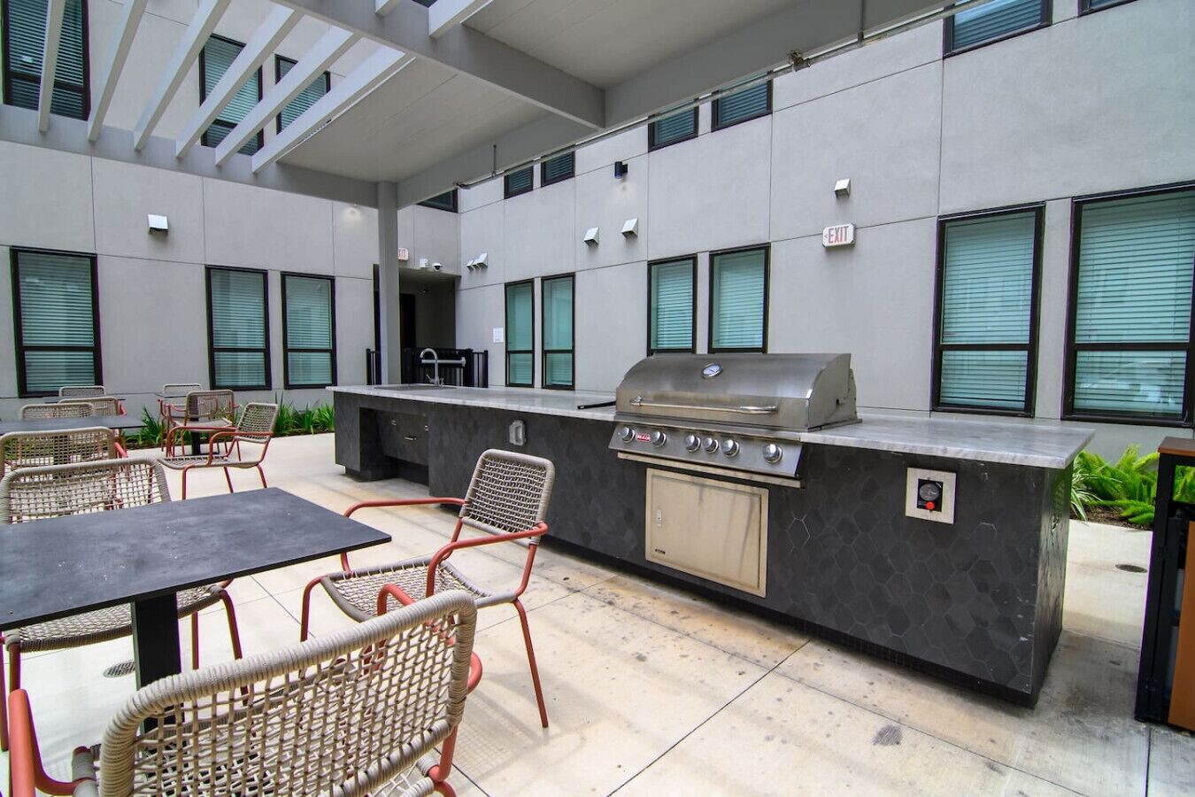 An outdoor patio with a grill, seating, and a view of the building's interior.